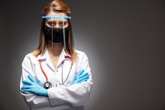 Woman of doctor with face mask looking at camera on gray background, corona virus concept.