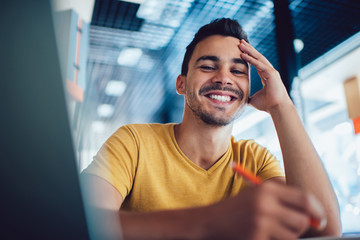 Smiling handsome male student enjoying learning process making notes for homework,portrait of...