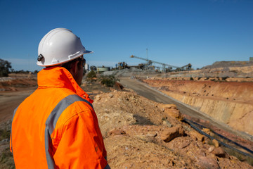 Unidentifiable miner in front of a copper mine portal road, with minehead in background in NSW...
