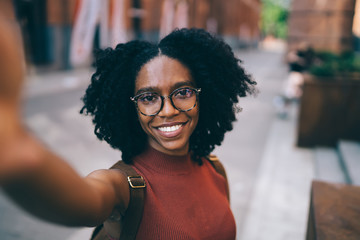 Young smiling black woman taking selfie in city