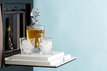 open hatch of a mini bar in a modern refrigerator. home mini bar in the fridge. a glass carafe full of whiskey, cognac or an alcoholic drink, ready to be poured into glasses