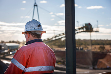 Unidentifiable miner in front of rock crusher at minehead in NSW Australia