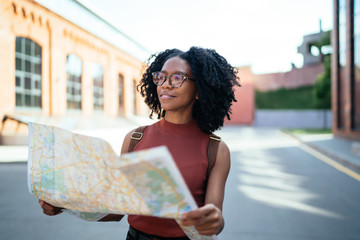 Female student on street and looking away from map in hands
