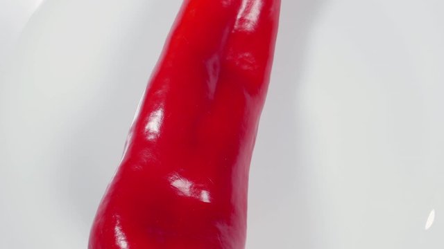 Top View Rotating Fresh Raw Ramiro Red Chili Pepper On A White Plate .