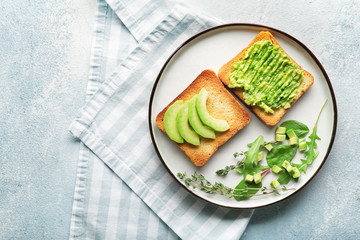 Plate with tasty avocado sandwiches on color background
