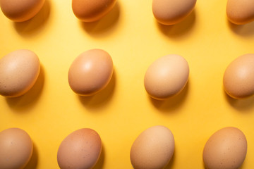 Fresh eggs aligned on yellow background seamlessly. Easter concept.