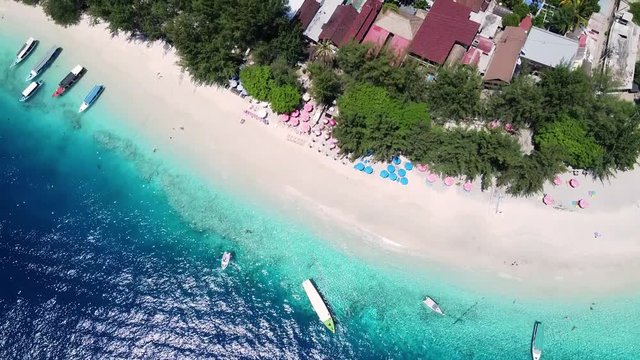 some boats filmed from the top with the drone, on the shore of the ocean near a beach in the tropical area, a blue and transparent water. Pleasant rest on the ocean.