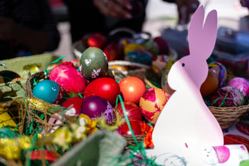 Colored Easter eggs in the basket, colored by children with pink paper bunny.