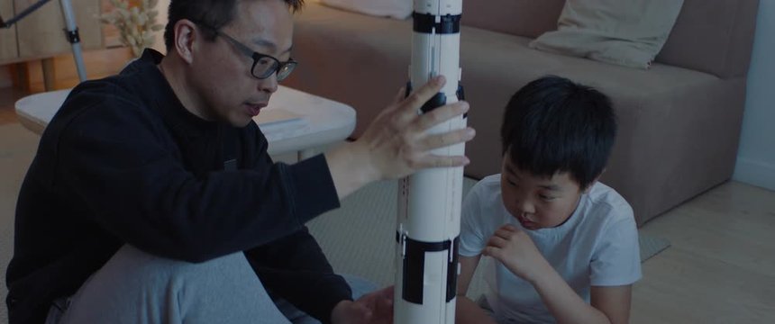 Chinese father and son playing together, building moon landing mission rocket together. Stay home, quarantine, science. Shot with ARRI Alexa Mini