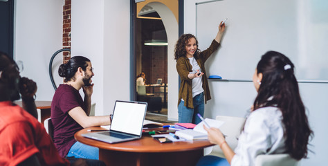Cheerful group of young diverse students studying together in college