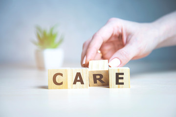 CARE - medical concept. Hand hold Wooden cubes and flower behind.