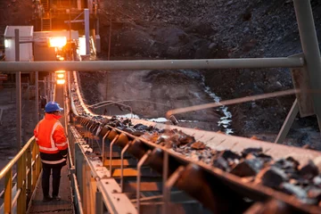 Nyngan Australia June 20th 2012 : Shallow depth of field image of a miner inspecting ore rocks on a conveyor in NSW Australia © Michael Evans