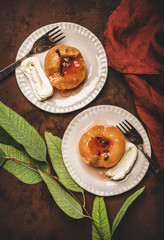 Flat-lay of Turkish traditional dessert with sweet quince boiled in sugar syrup and spices and heavy cream Kaymak on plates over rusty brown table background, top view. Turkish national cuisine