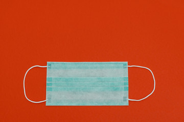 Antivirus face mask. Medicine face mask. Surgical mask with rubber ear straps.Prevention of virus, flu, colds and coronavirus. on red background with copy space.