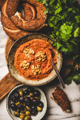 Flat-lay of Turkish traditional spicy smoked red pepper paste with walnuts and simit bagels over breakfast table, top view. Typical Turkish breakfast dish