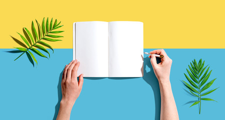 Person writing in a notebook from above