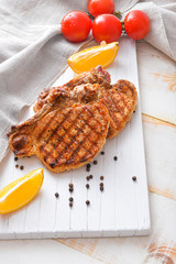 Board with cooked pork steaks on table