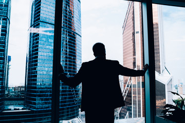 Businessman looking at city center through window in office