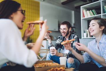 Laughing friends enjoying pizza during party