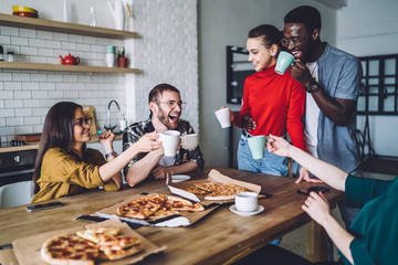 Content smiled multiethnic person rejoicing at table with pizza and drinks