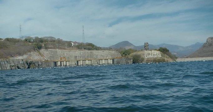 View of Chicoasen Dam from reservoir with Statues and CFE Sign