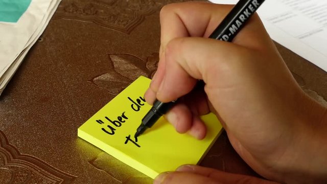 woman is writing "&uuml;ber den Tellerrand sehen" (think outside the box) on a post-it