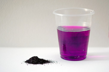 Potassium permanganate powder on a white background. Black powder potassium permanganate and a...