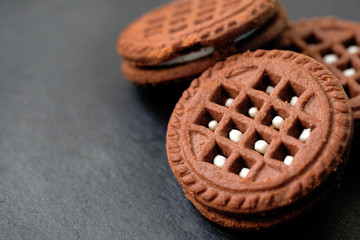 Close-up round chocolate chip cookies with white filling. Chocolate friable cookies on a black background. A delicious dessert for tea.