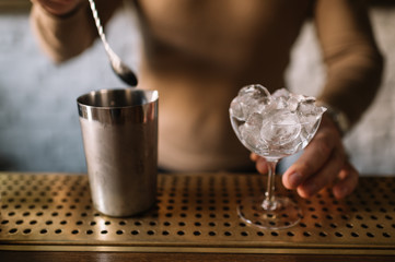 Bartender preparing cocktail based on gin, birch juice and spraying essential oil of frankincense...