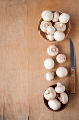 Still life: clay Cup and basket with mushrooms and a knife on a wooden background with space for text, top view