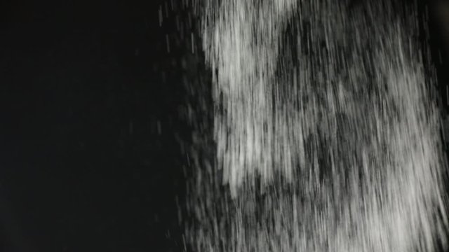 Flour sifting against on black background. Slow motion shot, closeup