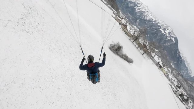 Extreme paragliding landing on a snowy day near Interlaken. Winter adventure and mountain landscape concept.