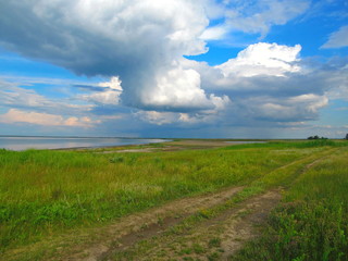 Green shore of the lake and blue sky with clouds. Lake Sivash, Crimean peninsula.