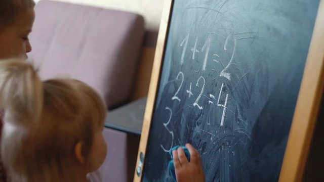 mother teaches her children math by drawing numbers on a blackboard with chalk. teaching children at home