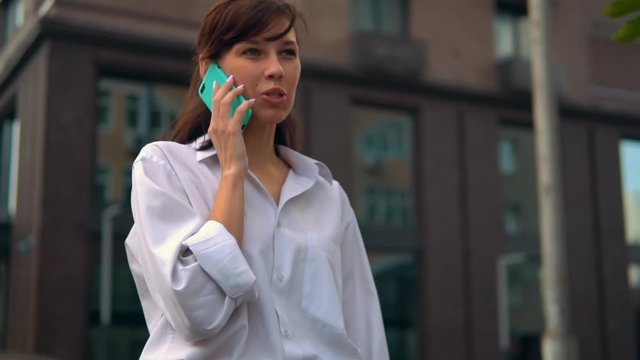 happy student talking by phone outdoors female in white casual shirt walking in city slow motion