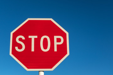 A bright red stop sign against a perfect blue sky.