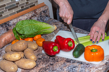 Woman cutting colorful vegetables for healthy salad
