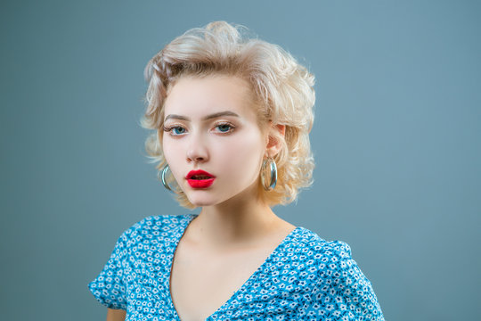 Close up portrait of young beautiful woman with pinup style, hoop earrings, posing on gray Isolated background. Copy, empty space for text.