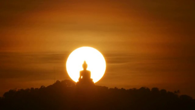 hue sunset behind silhouette Phuket big buddha statue on hilltop with many big trees high mountain in the beautiful evening colourful  orange twilight sky , attraction tourist photo spot