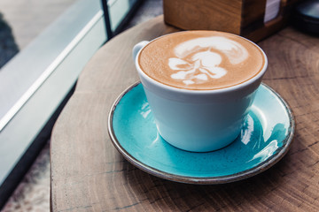 Soft focus on latte coffee cup. Hot milk art coffee on wooden table in cafe.