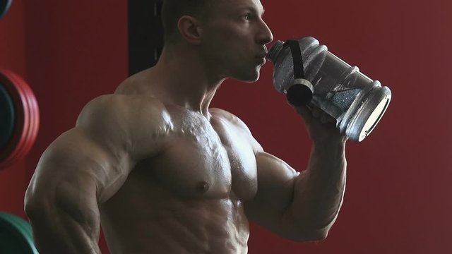 Sport muscular fitness man drinking and pouring water at face after workout cross fitness and bodybuilding concept gym background abs muscle exercises in gym naked torso fitness concept 
