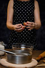 The confectioner prepares the dough, bread, cakes. Preparation and work with flour, eggs, milk and ingredients. Delicious food, recipes, cooking, gastronomy, on a dark background and wooden table.