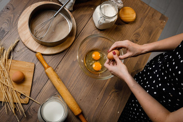 The confectioner prepares the dough, bread, cakes. Preparation and work with flour, eggs, milk and ingredients. Delicious food, recipes, cooking, gastronomy, on a dark background and wooden table.