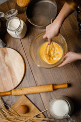 The confectioner prepares the dough, bread, cakes. Preparation and work with flour, eggs, milk and ingredients. Delicious food, recipes, cooking, gastronomy, on a dark background and wooden table.