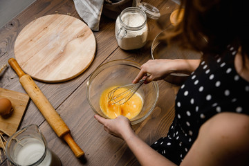 The confectioner prepares the dough, bread, cakes. Preparation and work with flour, eggs, milk and ingredients. Delicious food, recipes, cooking, gastronomy, on a dark background and wooden table.