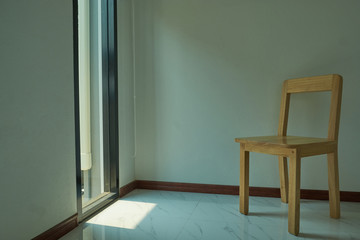 Wooden chair is located in the empty room on the white wall.