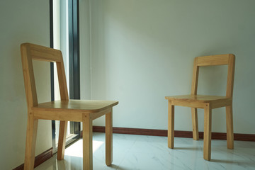 Two wooden chair is located in the empty room on the white wall.