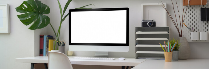 Close up view of minimal office room with blank screen computer, office supplies and decorations on...