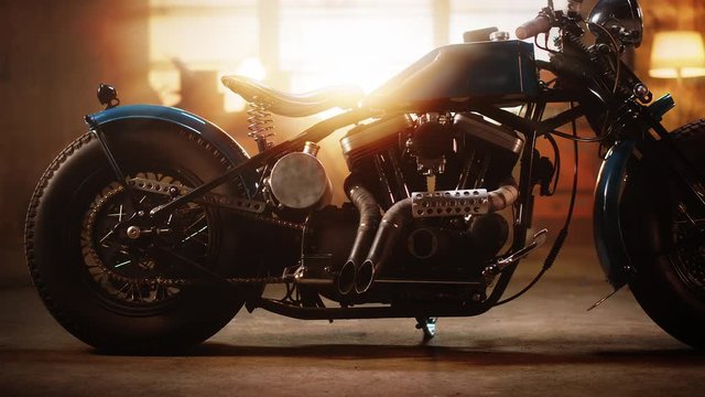 Custom Bobber Motorbike Standing in an Authentic Creative Workshop. Vintage Style Motorcycle Under Warm Lamp Light in a Garage. Profile View.