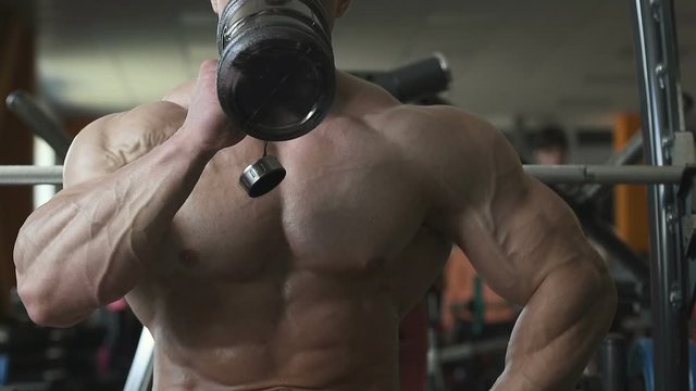 Sport muscular fitness man drinking and pouring water at face after workout cross fitness and bodybuilding concept gym background abs muscle exercises in gym naked torso fitness concept 
